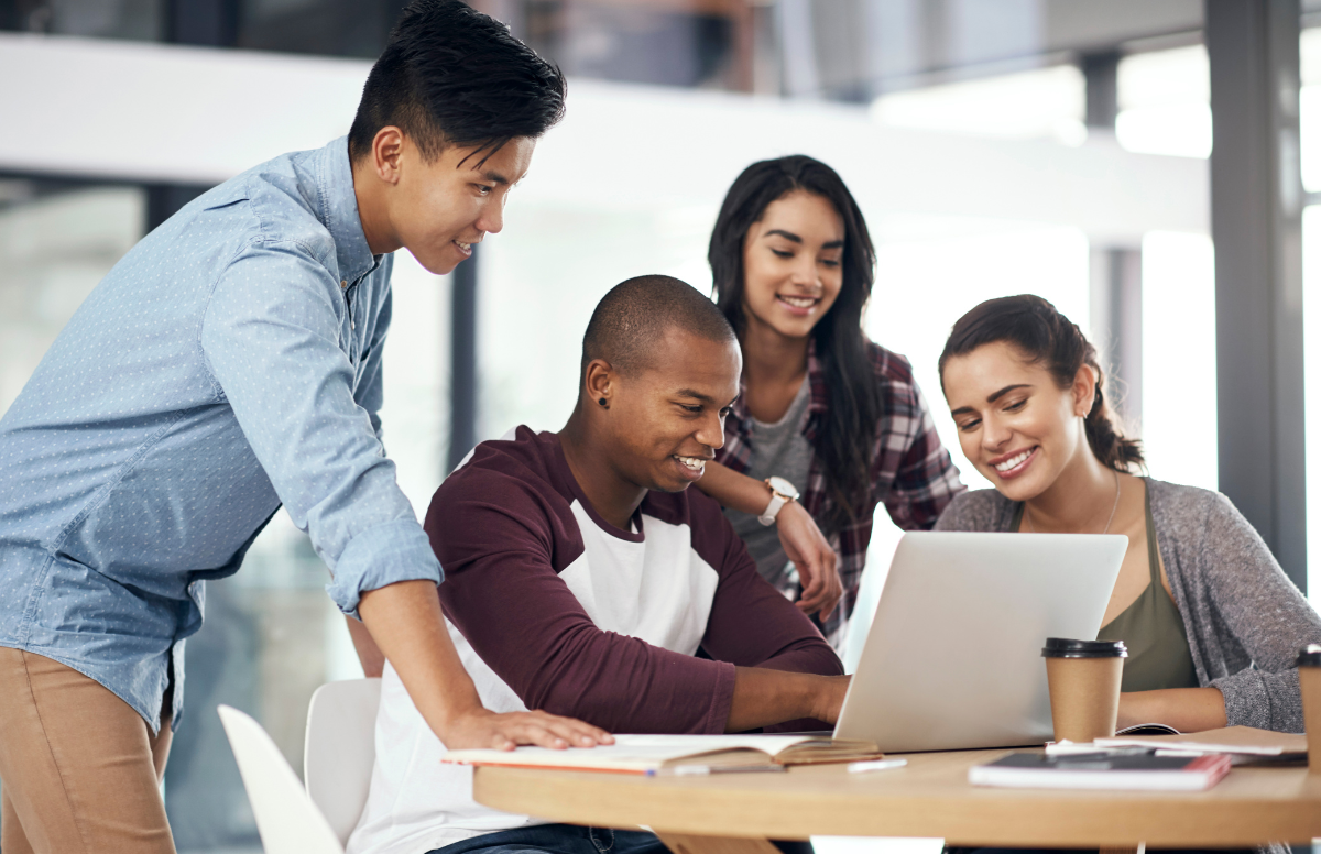group of colleagues look at a laptop together