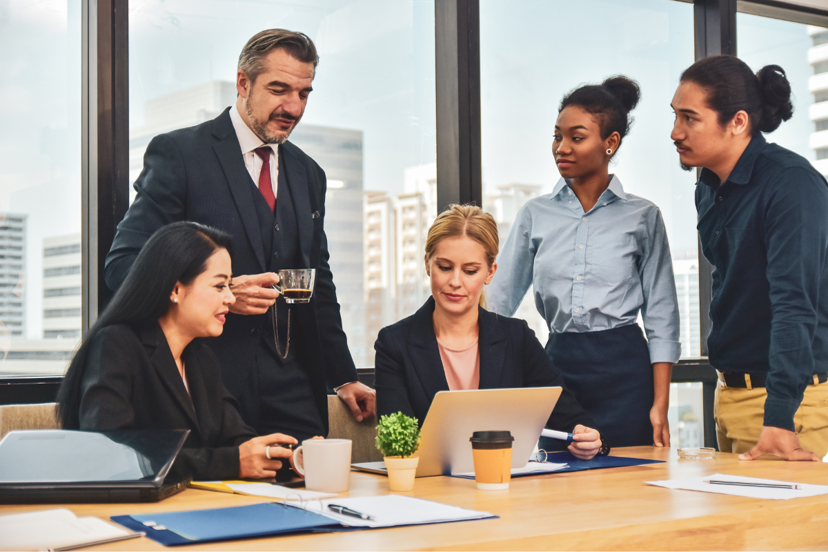 group of employees surround a laptop in discussion